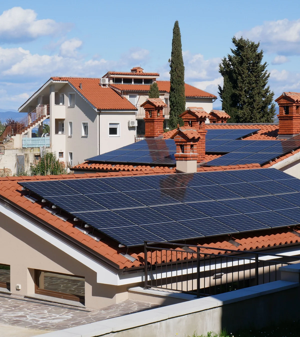 Deretan rumah dengan panel surya di atap genteng, manfaat beralih ke tenaga surya bersama Solar Panel Mandiri