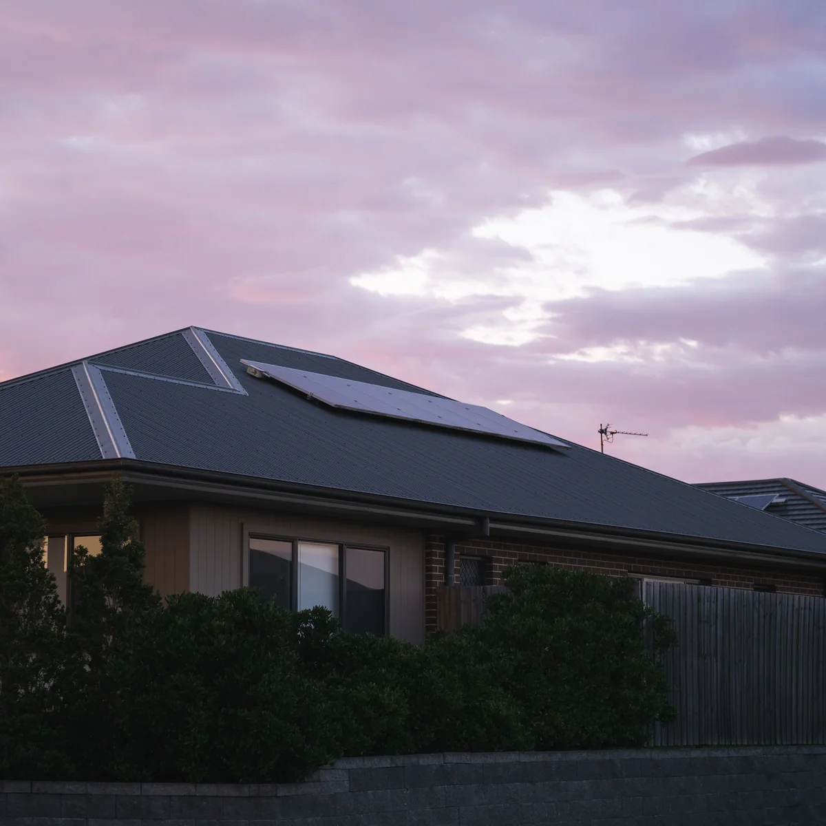 Panel surya PLTS on-grid terpasang di atap rumah saat senja, dipasang oleh Solar Panel Mandiri